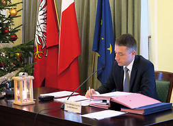 Przewodniczący Sejmiku Województwa Mazowieckiego Ludwik Rakowski siedzi przy biurku, na którym stoi lampion z Betlejemskim Światełkiem Pokoju