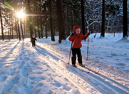 Po ośnieżonych ścieżkach na nartach biegną dzieci