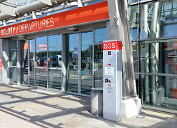 wejście do hali odlotów modlińskiego lotniska z widocznym panele SOS