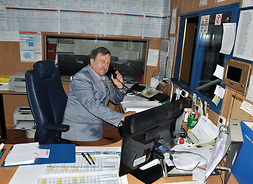 pan Marek w swoim miejscu pracy - rozmawia przez telefon przy biurku, na którym leżą różne papiery i dokumenty