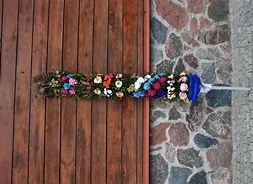 Palma wykonana przez Julię Maszerowską z kolorowymi kwiatami z bibuły i trawami, ustawiona pionowo