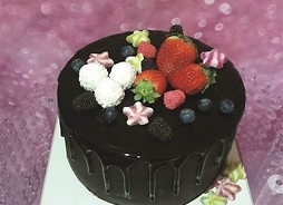 tort oblany ciemną czekoladą na wierzchu świeże owoce
