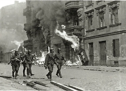Pięciu SS-manów idących przed płonącą kamienicą