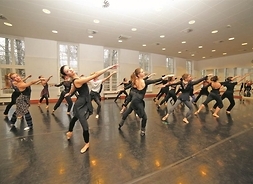 Sala baletowa, w niej duża grupa tancerek w strojach gimnastycznych