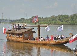 Drewniany statek płaskodenny na środku Wisły, w tle Most Śląsko-Dąbrowski