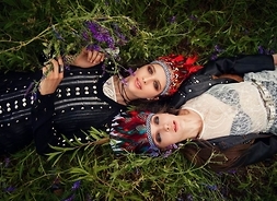 dwie kobiety leżą na trawie w odworotnych kierunkach, mają głowy obok siebie