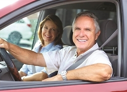 Dwoje starszych ludzi sfotografowanych przez okno od strony kierowcy w aucie