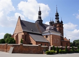 Widok na kościół z cegły z dwiema wieżami i okalającym niewysokim murem