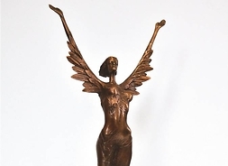 Figurka przedstawiająca kobietę z uniesionymi do góry ramionami-skrzydłami