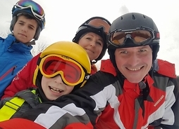 uśmiechnięci rodzice i dzieci w strojach narciarskich pozują do zdjęcia