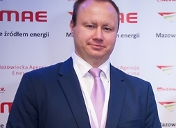 członek zarządu Mazowieckiej Agencji Energetycznej na tle banera  firmy