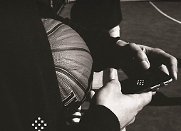 Logotyp BallSquad. Widoczne są dłonie trzymające telefon komórkowy oraz piłkę do gry