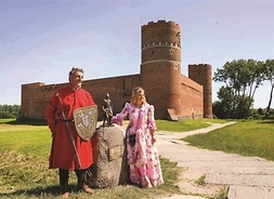 Kobieta i mężczyzna w strojach średniowiecznych stoją obok pominika rycerza