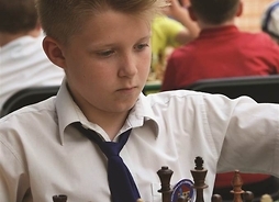 skupiony chłopiec patrzy na szachownicę