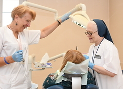 lekarz stomatolog Joanna Gąbka podczas pracy z pacjentem, obok stoi kierownik Poradni Ogólnostomatologicznej Hanna Wąsowicz-Cićkiewicz