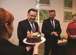 Marszałek Adam Struzik z tortem, na którym stoją świeczki z cyfrą 18