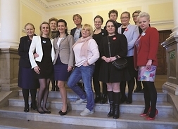 w pomieszczeniu na schodach do zdjęcia pozuje grupa kilkunastu kobiet