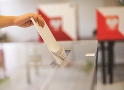 urna, do której wrzucana jest karta. widać tylko dłoń wyborcy