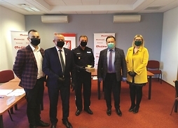 Grupa oób w maskach ochronnych pozująca do wspólnego zdjęcia z marszałkiem Adamem Struzikiem