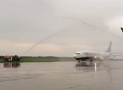 na płynie lotniska stoi samolot, na który z wozu strażackiego wylewana jest woda