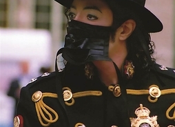 Piosenkarz Michael Jackson w kapeluszu na głowie i maseczce na twarzy podczas rozdawania autografów.