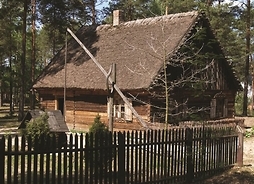 drewiany dom otoczony płotem i drzewami