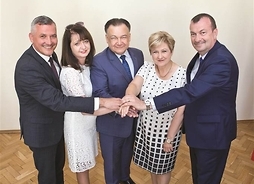 grupa pięciu osób trzyma się za ręce i pozuje do zdjęcia