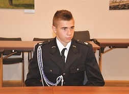 młody strażak w mundurze siedzi przy stole