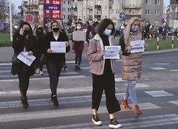 Młode kobiety z planszami, na których wypisane są hasła strajkowe, przechodzą przez jezdnię