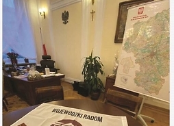 zrzut ekranu, na którym widać biurko i leżącą na nim flagę Radomia