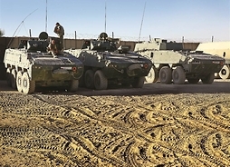 Żołnierze biorący udział w misji siedzący na transporterach opancerzonych
