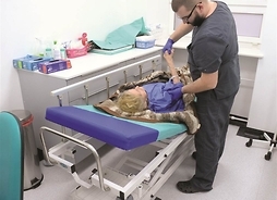 Rehabilitant wykonujący zabieg u kobiety leżącej na medycznym łóżku.