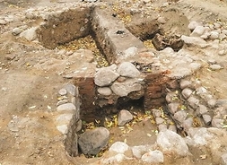 Wykopaliska fundamentów wieży. W rozkopanym piachu widać fragmenty muru