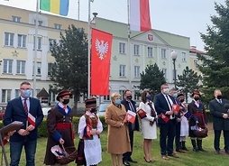 na maszcie wisi flaga Mazowsza, obok stroi grupka osób, trzy z nich w strojach ludowych