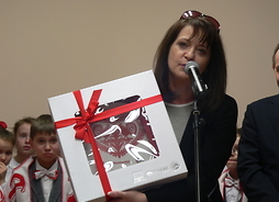 członek zarządu Janina Ewa Orzełowska przekazuje mieszkańcom prezent z okazji otwarcia świetlicy
