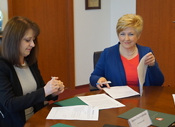 Wicemarszałek Janina Ewa Orzełowska i członek zarządu województwa mazowieckiego Elżbieta Lanc podpisują umowy na inwestycje dofinansowywane przez Unię Europejską