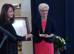 Wicemarszałek Ewa Janina Orzełowska przekazuje medal pamiątkowy na ręce dyrektor szkoły w Samorządkach