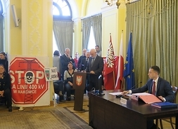 Przy stole prezydialnym siedzi przewodniczący sejmiku, przy mównicy przemawia radny Stefan Kotlewski. Za nim stoją protestujący mieszkańcy