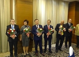 polska delegacja stoi z kwiatami w dłoniach