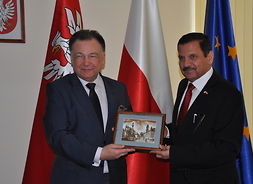 Marszałek Adam Struzik trzyma wspólnie z ambasadorem rycinę przedstawiającą Stare Miasto w Warszawie