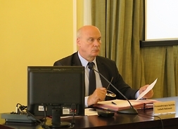 przy stole prezydialnym siedzi wiceprzewodniczący Sejmiku Województwa Mazowieckiego Tomasz Kucharski