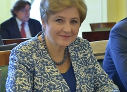 członek zarządu Elżbieta Lanc pozuje do zdjęcia, siedzi przy stoliku