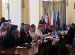 Przy stole siedzą radni Klubu Platformy Obywatelskiej. W tle przy mównicy przemawia radny Radosław Fogiel