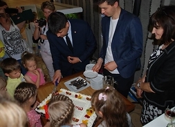 dzieci przyglądają się krojeniu tortu przez organizatorów
