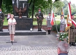 przemawia Elżbieta Lanc w tle pomnik AK