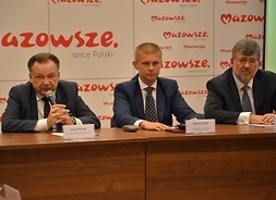 Marszałek przemawia przez mikrofon, obok Dariusz Grajda prezes Polskiego Związku Samorządowych Przewoźników Kolejowych i Robert Stępień