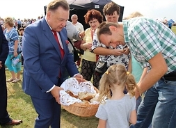 Marszałek Adam Struzik dzieli się chlebem z dziewczynką i jej ojcem