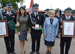 przedstawicieli Samorządu Mazowsza i strażacy, kórzy trzymają medal i dyplom