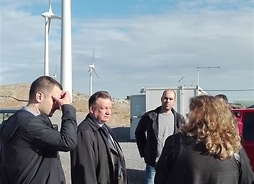marszałek i dyrektor departamentu Rozwoju i Funduszy Strukturalnych UMWM rozmawiają z właścicielami farmy w tle widać wiatraki