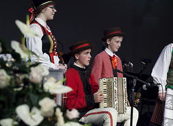 na scenie młodzi członkowie zespołu folklorystycznego w tradycyjnych strojach ludowych